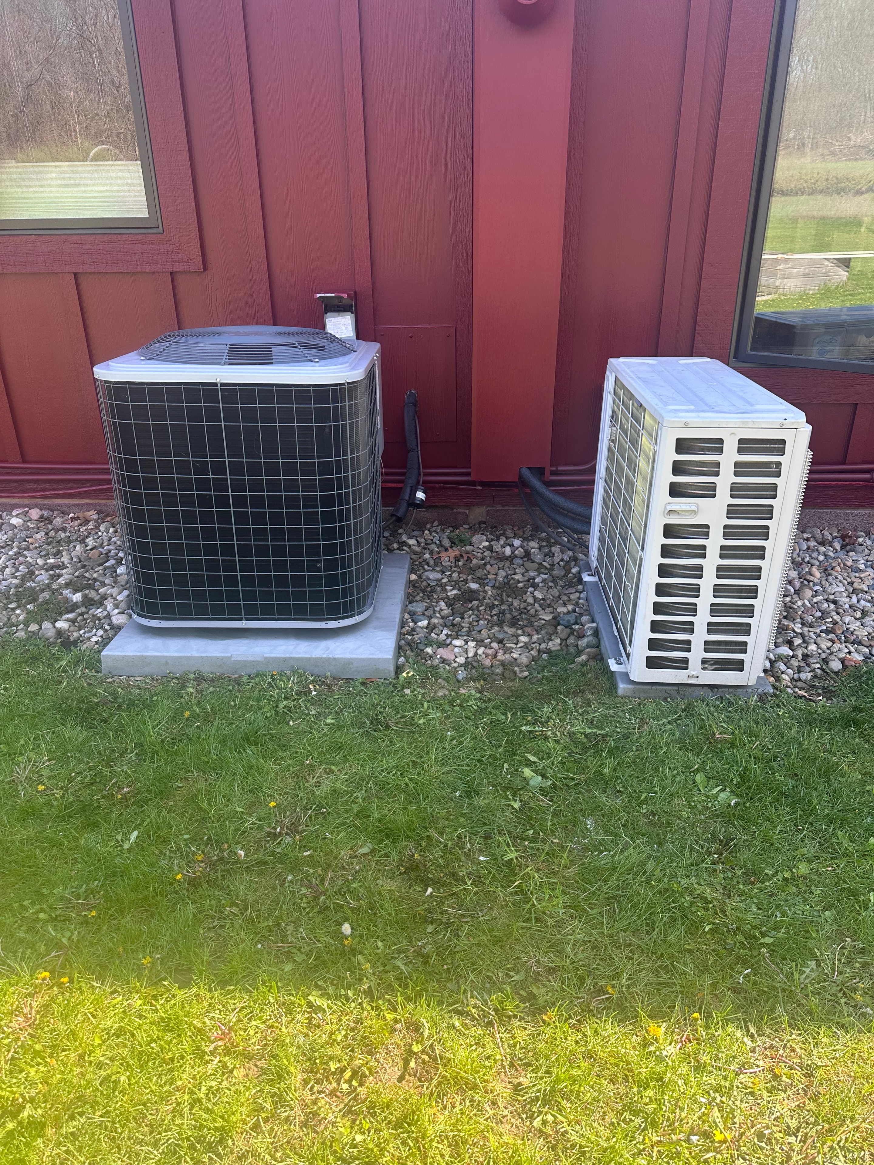 Two outdoor AC condenser units alongside a residential home serviced by HomeFlow in Chelsea, Michigan